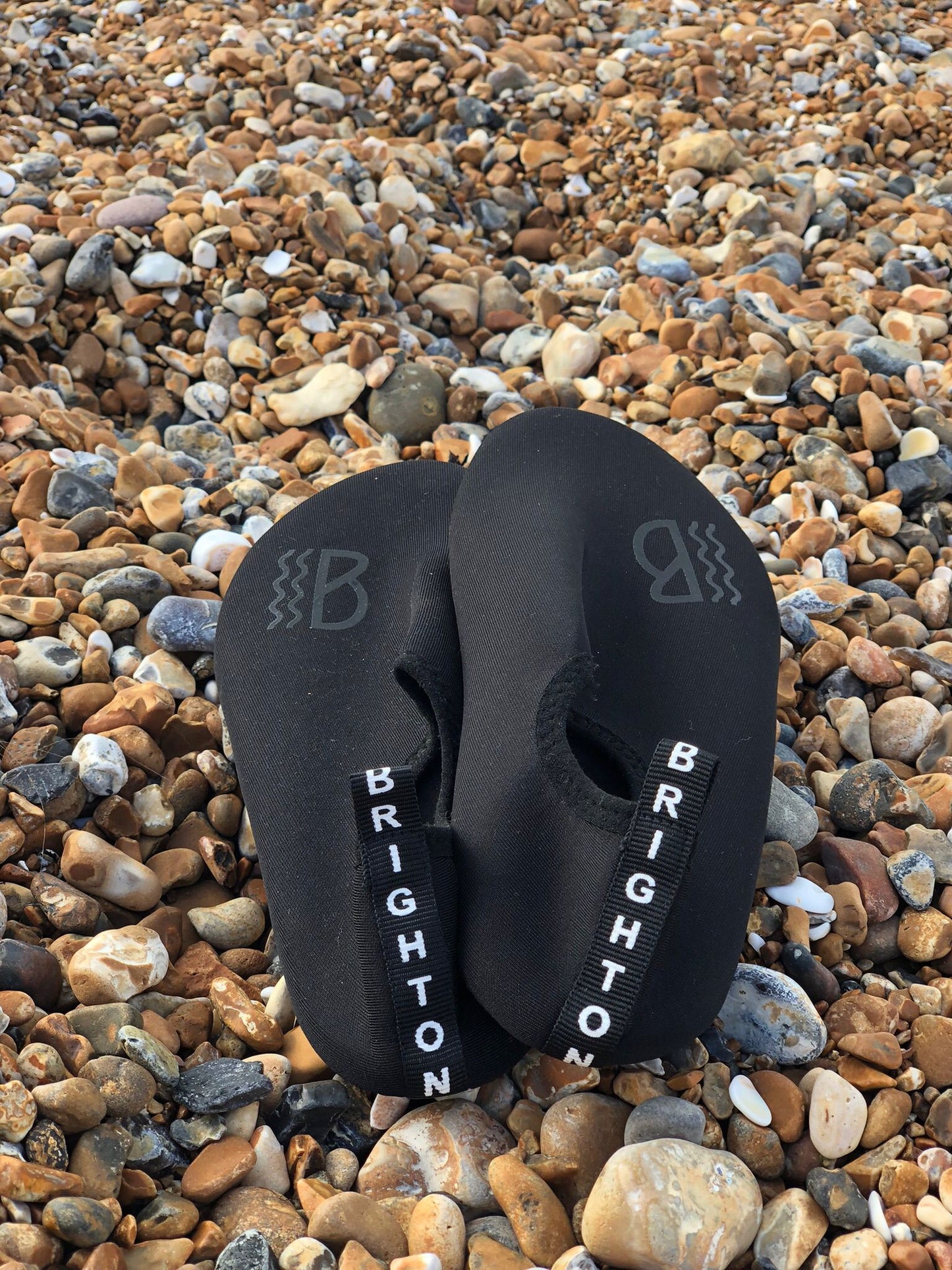 Black neoprene water shoes with 'Brighton' branding on pebbles